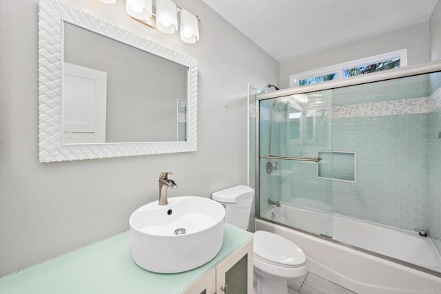 full bathroom featuring toilet, vanity, and shower / bath combination with glass door