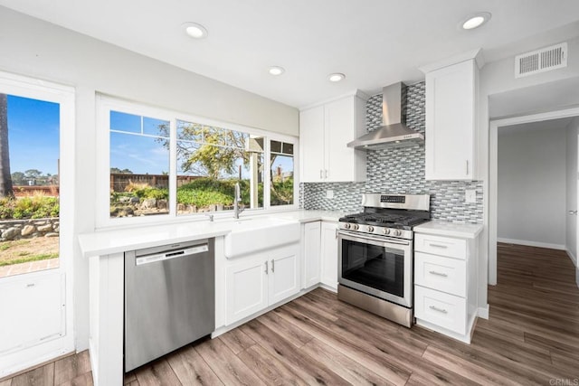 kitchen with sink, stainless steel appliances, white cabinets, and wall chimney exhaust hood