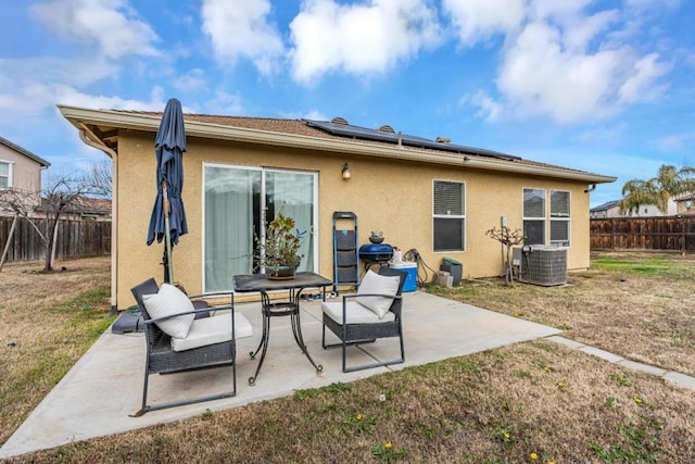 rear view of house with central AC, a lawn, solar panels, and a patio area