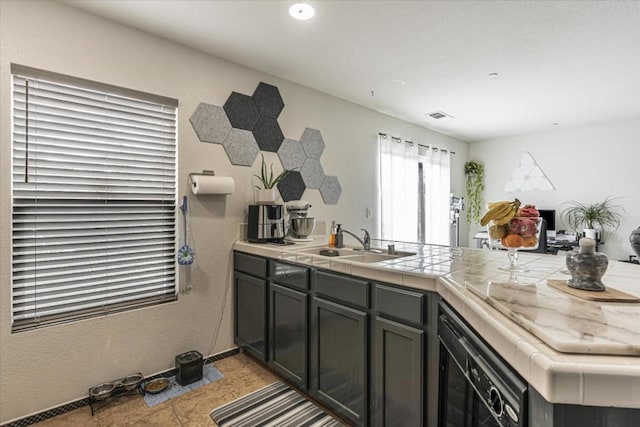 kitchen featuring tile countertops, kitchen peninsula, sink, and light tile patterned floors