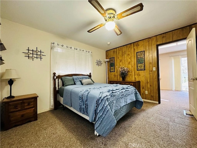 carpeted bedroom with ceiling fan and wooden walls