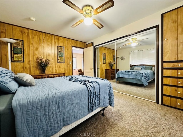 bedroom featuring wooden walls, ceiling fan, carpet flooring, and a closet