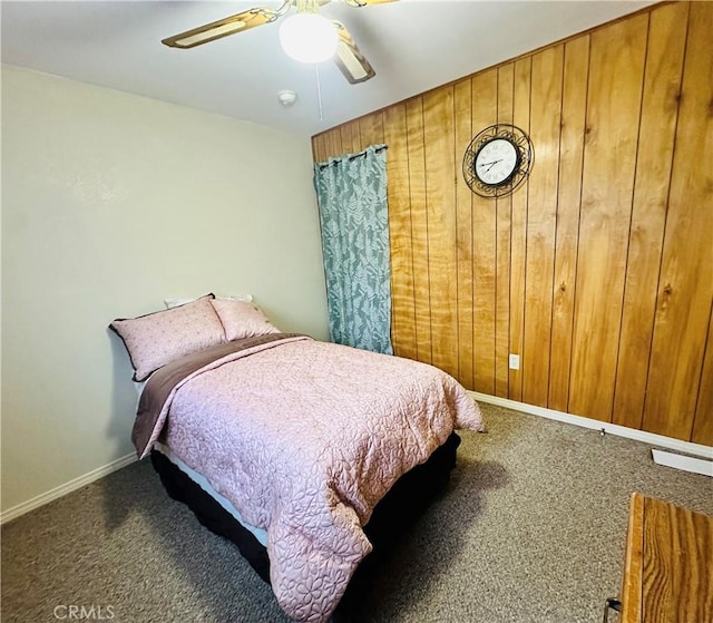 bedroom with carpet flooring, ceiling fan, and wood walls