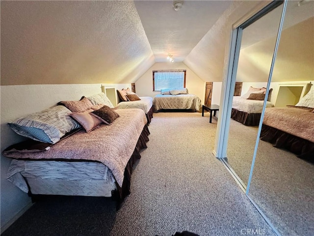 bedroom with vaulted ceiling, a closet, a textured ceiling, and carpet flooring