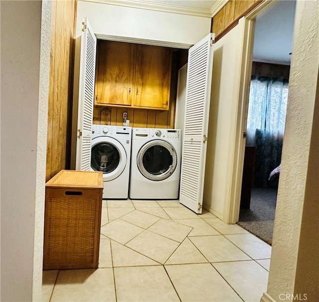 laundry room featuring crown molding, washer and clothes dryer, cabinets, and light tile patterned flooring