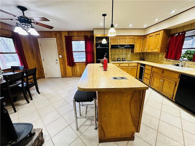 kitchen with sink, decorative light fixtures, black appliances, a kitchen island, and backsplash