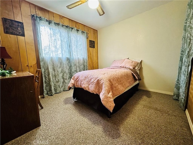 carpeted bedroom with ceiling fan and wooden walls