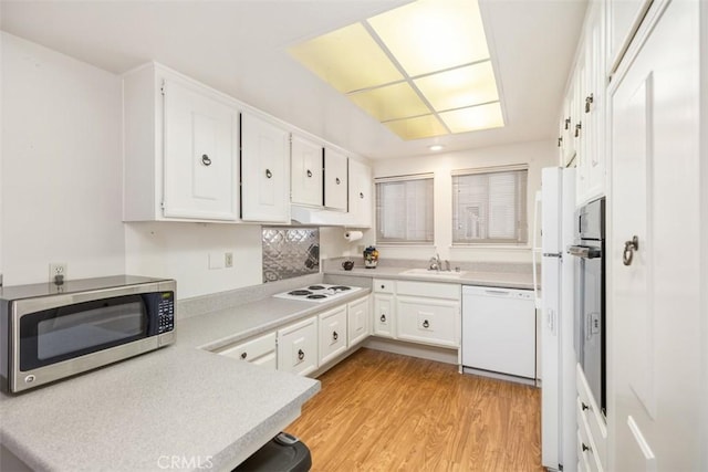 kitchen with sink, white cabinets, white appliances, and light hardwood / wood-style floors