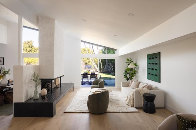 living room with plenty of natural light, high vaulted ceiling, and light wood-type flooring