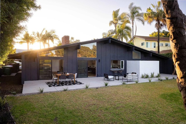 back house at dusk with a yard and a patio area