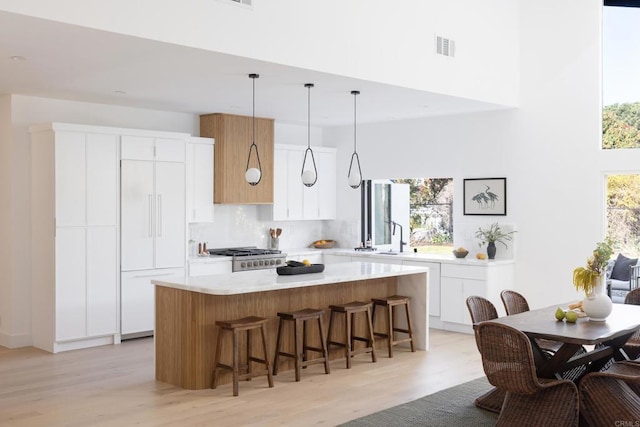 kitchen featuring a kitchen bar, hanging light fixtures, a kitchen island, decorative backsplash, and white cabinets