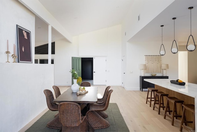 dining area featuring a high ceiling and light wood-type flooring