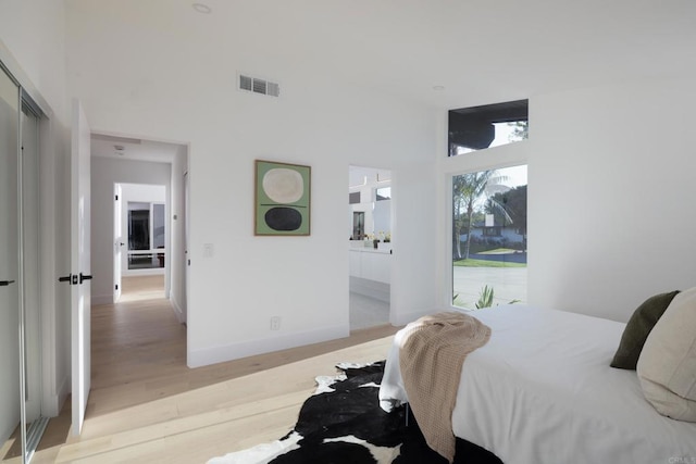 bedroom featuring light wood-type flooring and a high ceiling