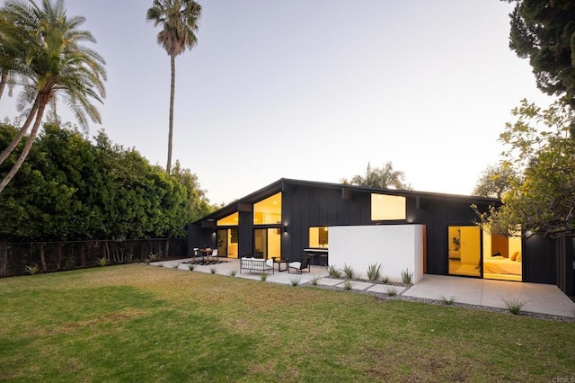 rear view of property with a yard, a patio area, and an outdoor living space with a fire pit