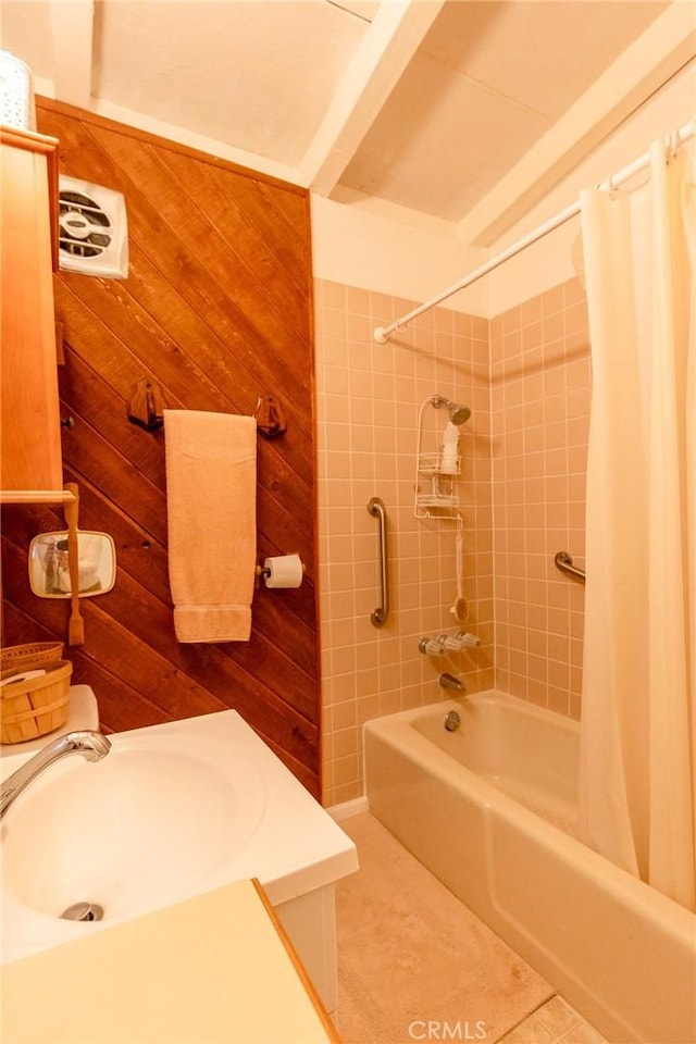 bathroom featuring sink, wooden walls, tile patterned floors, and shower / bath combination with curtain