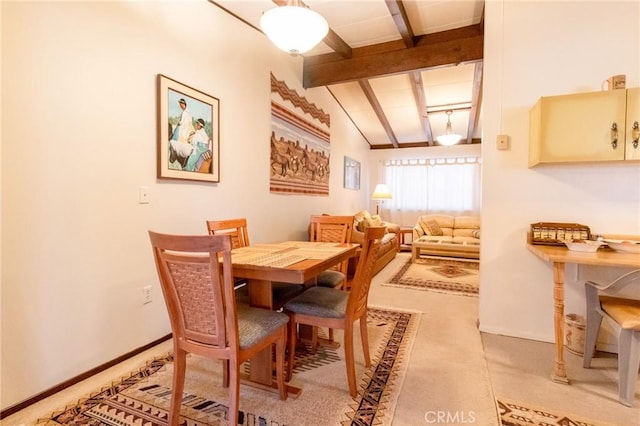 dining room featuring vaulted ceiling with beams and light colored carpet