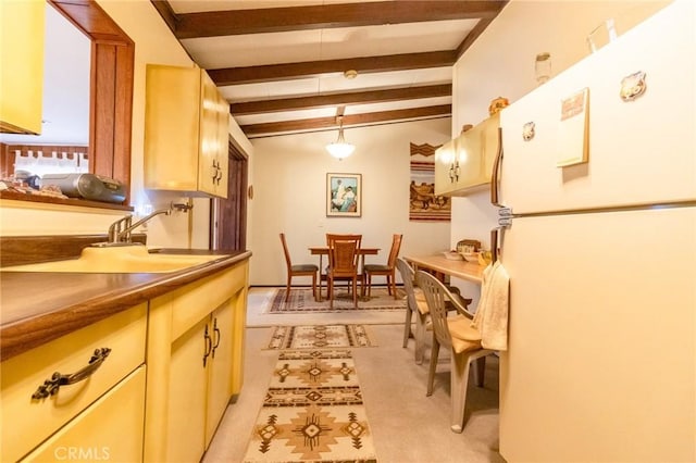 kitchen with lofted ceiling with beams, white fridge, sink, and decorative light fixtures