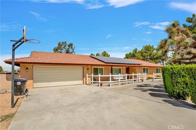 ranch-style home with a garage and solar panels