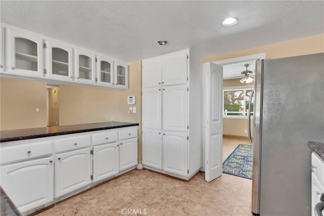 kitchen featuring stainless steel refrigerator, ceiling fan, and white cabinets