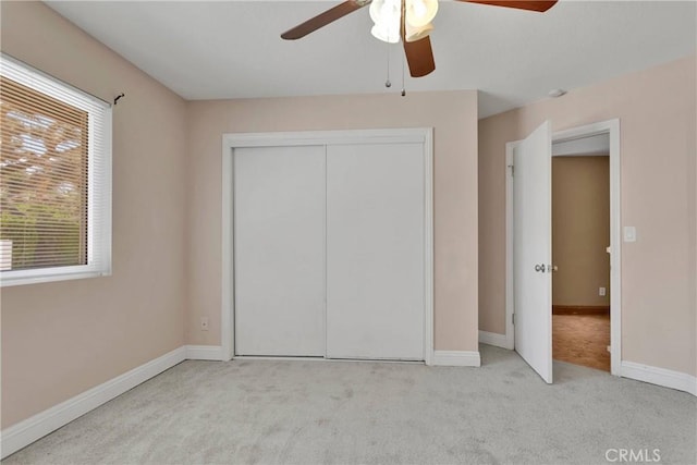 unfurnished bedroom with ceiling fan, light colored carpet, and a closet