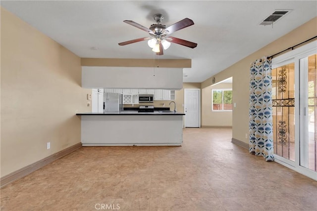 kitchen with appliances with stainless steel finishes, white cabinetry, sink, ceiling fan, and kitchen peninsula