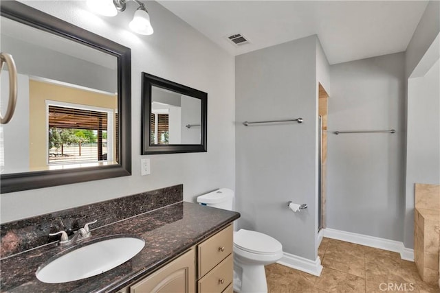 bathroom featuring vanity, tile patterned flooring, toilet, and walk in shower