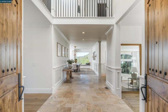 foyer entrance featuring ornate columns, ornamental molding, a towering ceiling, and light hardwood / wood-style flooring