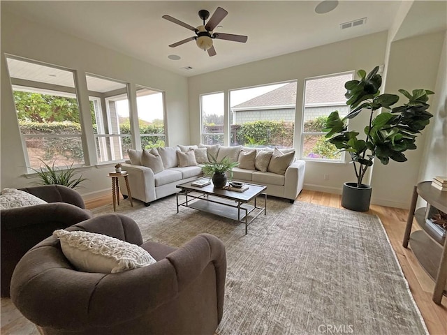 living room featuring light wood finished floors, visible vents, ceiling fan, and baseboards