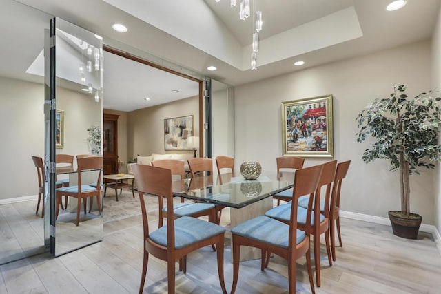 dining space featuring a tray ceiling and light wood-type flooring