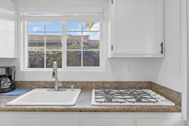 interior details featuring white cabinetry, sink, and white gas cooktop