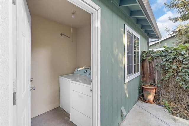 clothes washing area featuring separate washer and dryer and wood walls