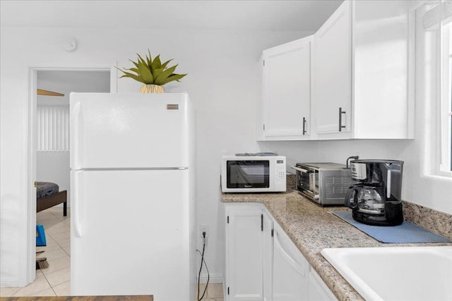 kitchen with white cabinetry, light tile patterned floors, and white appliances