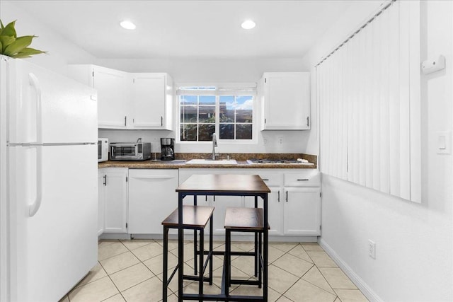 kitchen with sink, white appliances, white cabinets, and light tile patterned flooring