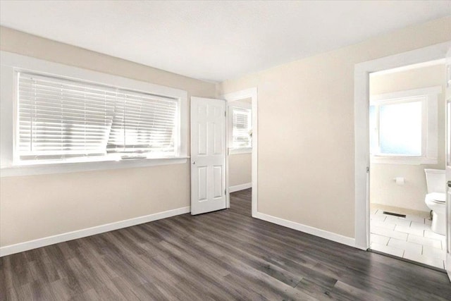 unfurnished bedroom featuring dark hardwood / wood-style floors and connected bathroom