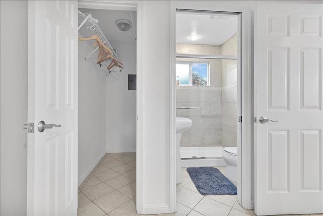 bathroom with toilet, an enclosed shower, and tile patterned flooring