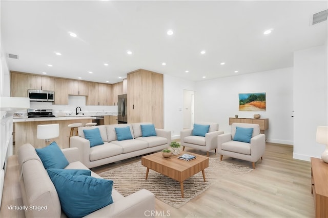 living area featuring light wood-type flooring, visible vents, and recessed lighting