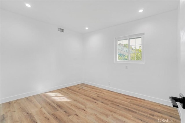 empty room featuring baseboards, light wood-style floors, visible vents, and recessed lighting