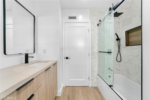 bathroom featuring vanity, shower / bath combination with glass door, wood finished floors, and visible vents