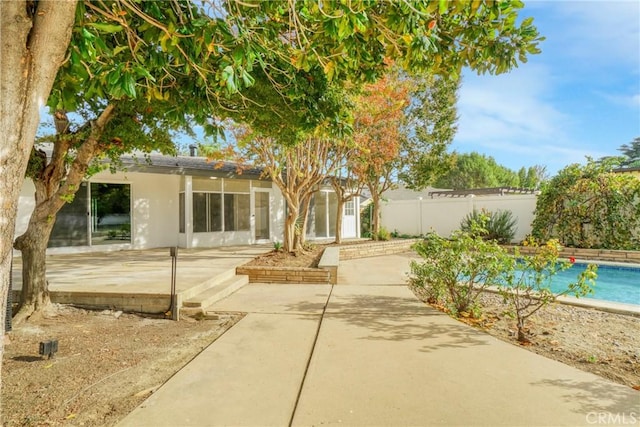 view of front facade with stucco siding, fence, and a patio