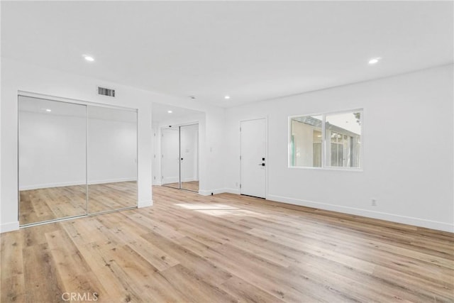 interior space with recessed lighting, visible vents, baseboards, light wood finished floors, and two closets