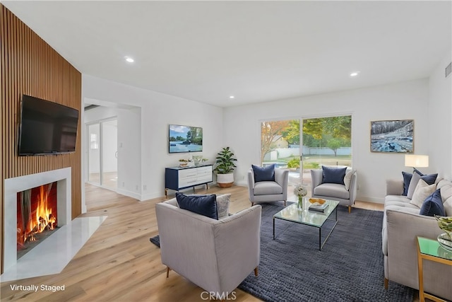 living room featuring recessed lighting, a fireplace with flush hearth, visible vents, baseboards, and light wood-type flooring