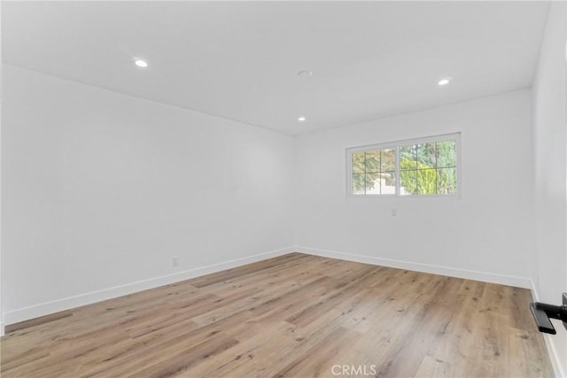 spare room featuring recessed lighting, light wood-style flooring, and baseboards