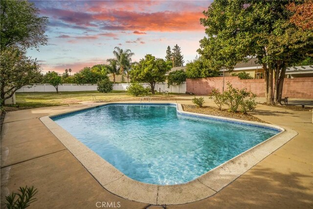 pool at dusk featuring a patio