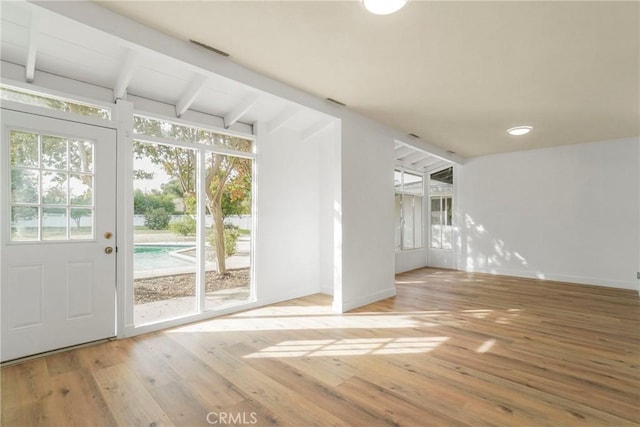 interior space featuring vaulted ceiling with beams, baseboards, and wood finished floors