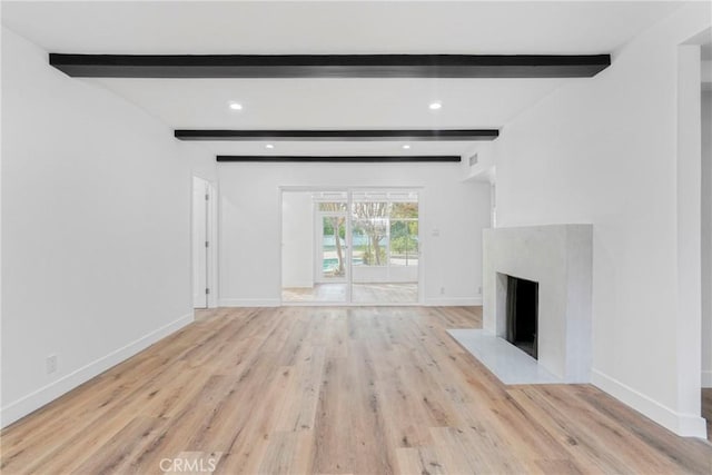 unfurnished living room featuring a fireplace with flush hearth, beam ceiling, light wood-style flooring, and baseboards