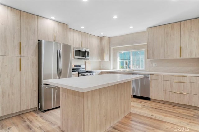 kitchen with light brown cabinetry, appliances with stainless steel finishes, light countertops, and a center island