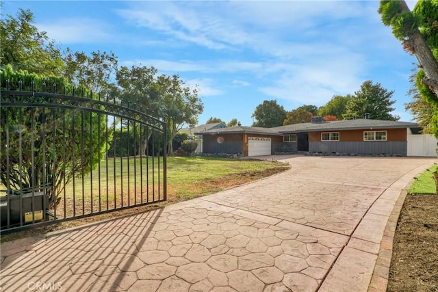 ranch-style home with a garage, fence, concrete driveway, and a front yard