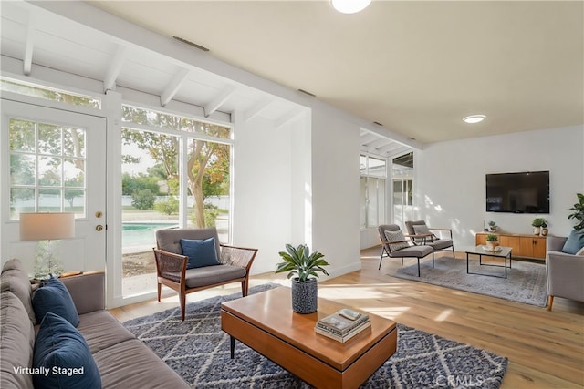 living room with lofted ceiling with beams and wood finished floors