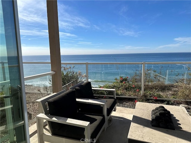 view of patio / terrace featuring a water view, a balcony, and a beach view