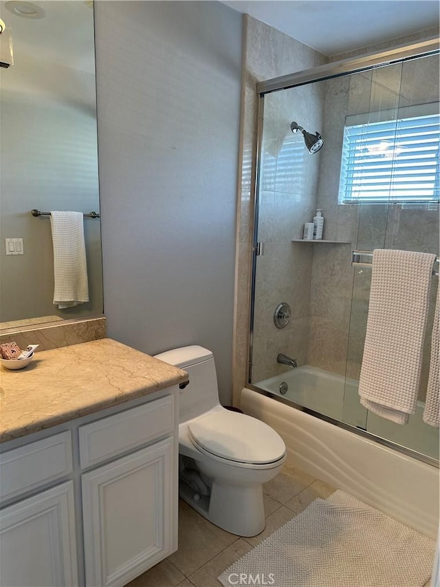 full bathroom with tile patterned flooring, bath / shower combo with glass door, vanity, and toilet